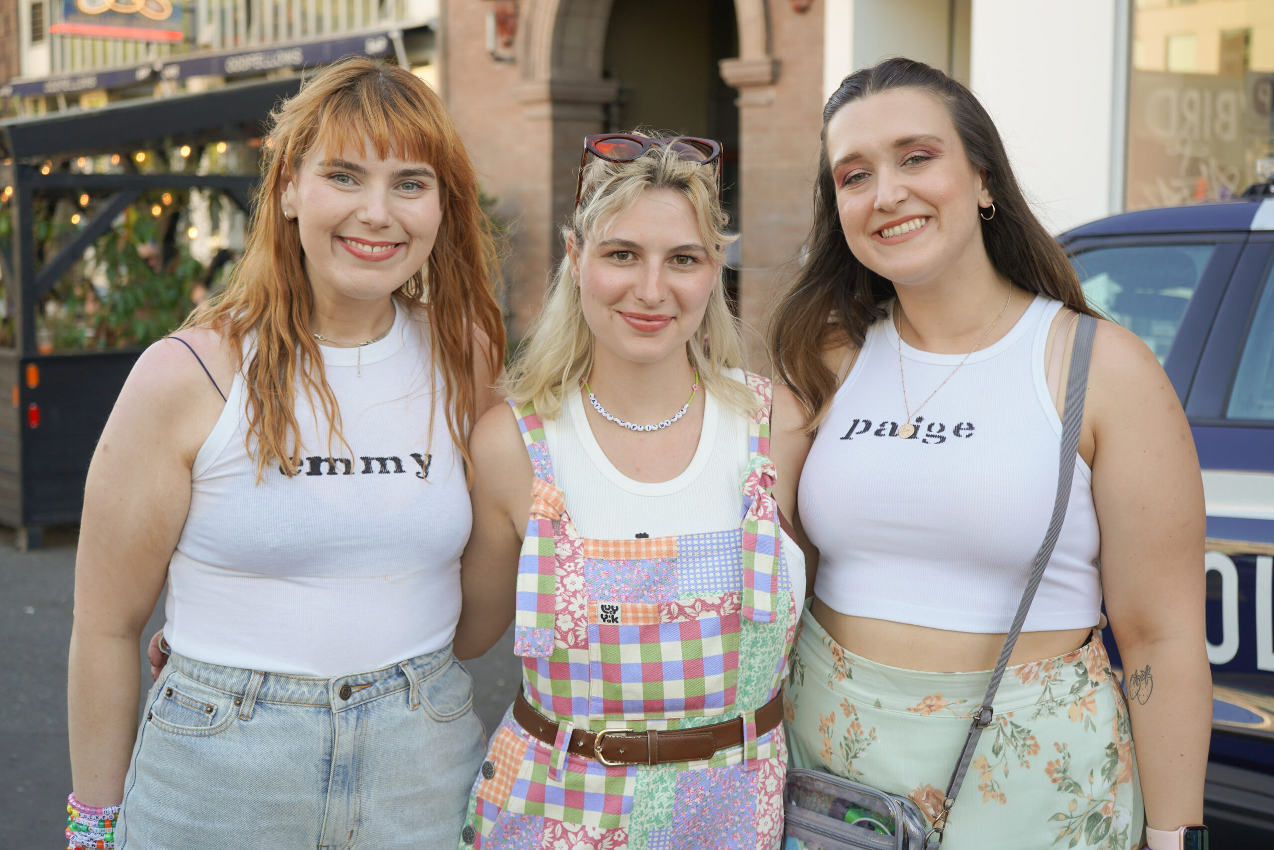 From left to right, friends Emmy Corliss, Kenzie Lundborg, and Paige Jarzabkowski on their way to see musician Muna wearing name shirts inspired by a recent Muna music video.